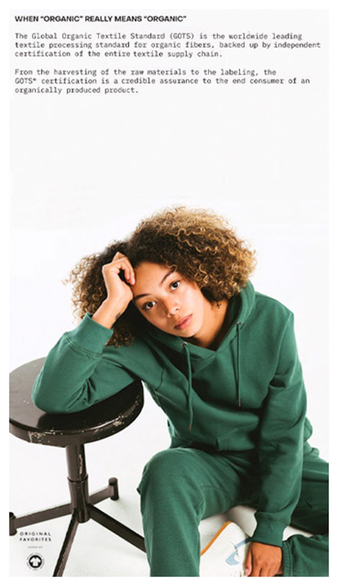 Model sitting down wearing an Original Favorites GOTS certified organic cotton hoodie.