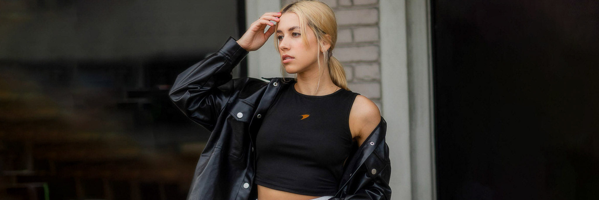 Woman in a black cropped tank top featuring a custom Mclaren F1 team logo.