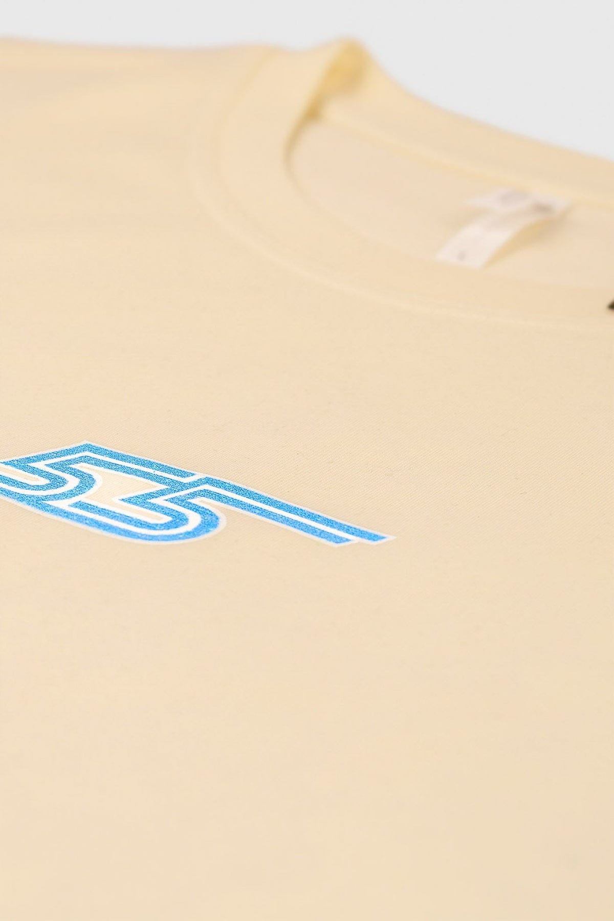 Beige t-shirt with blue number '55' logo printed on the front center with a light gray background
