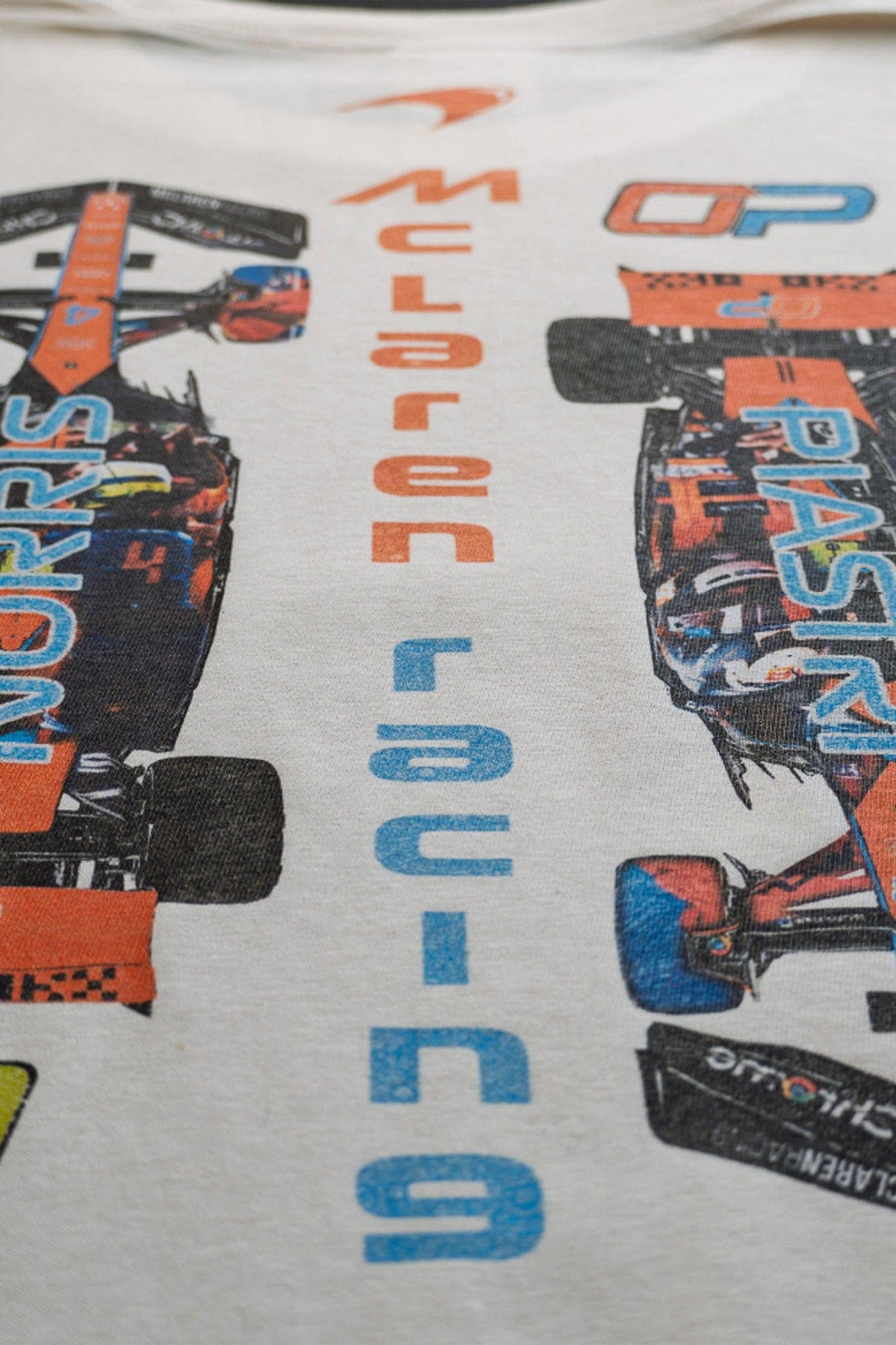 Back of a bay Comfort Colors shirt, featuring a text collage design that for the Mclaren F1 race cars.